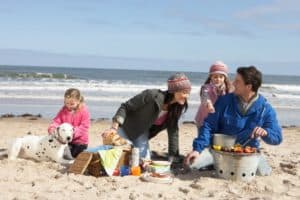 Famiie macht mit ihrem Hund einen Ausflug am Strand.