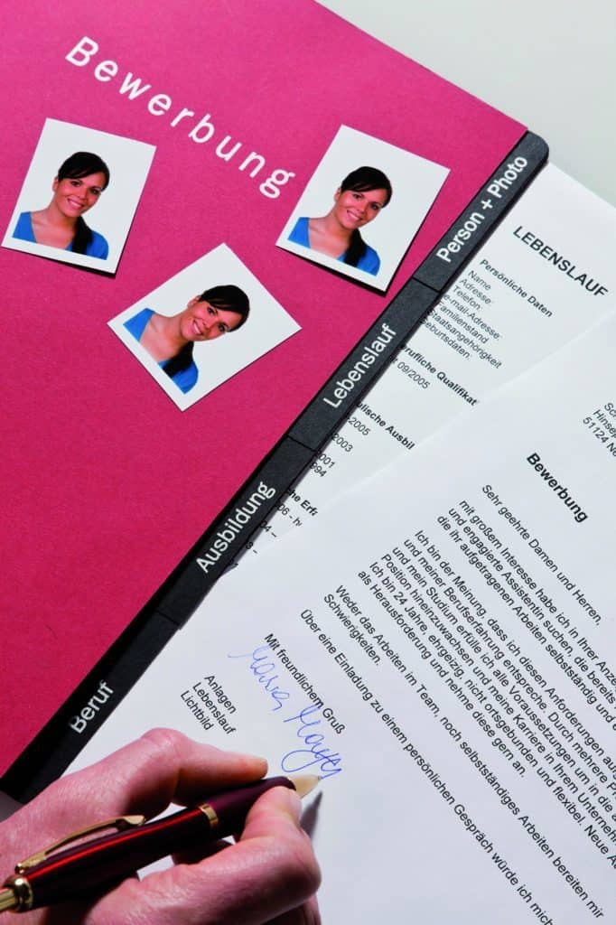 Eine pinkfarbene Bewerbungsmappe mit Anschreiben und Bwerbungsfotos.