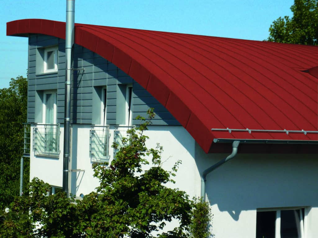 Modernes Haus mit grauer Fassade und rotem Dach aus Zink