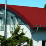 Modernes Haus mit grauer Fassade und rotem Dach aus Zink