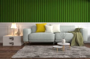 Die Wandgestaltung hinter dem grauen Sofa mit weißer Holztäfelung und grün gestreifter Mustertapete bringt Frische in die eigenen vier Wände.