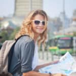Reisen mit kleinem Budget: junge Frau mit Rucksack und Stadtkarte in der Stadt.