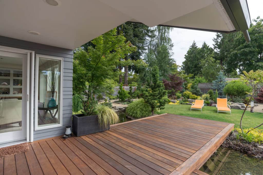 Eine Holzterrasse verbindet harmonisch Haus und Garten.