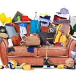 Entrümpeln: Sofa mit altem Krempel wie Schuhe, Bällen Taschen und Kleidungsstücke.