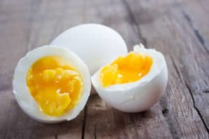Lebensmittel-Lifehacks, Nummer 5: Auf einem Holztisch liegt ein ganzes und ein halbiertes gekochtes Ei