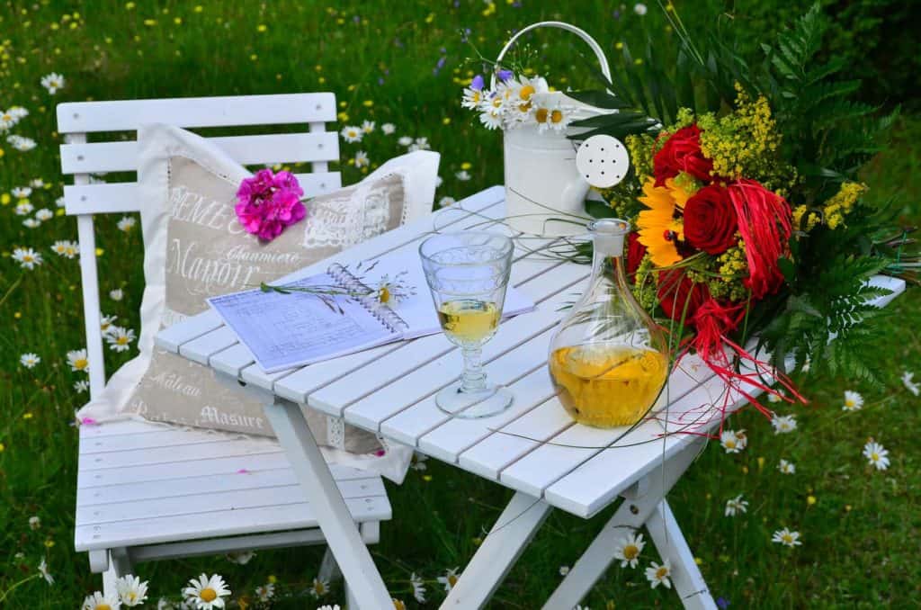 Eine romantische Ecke im Garten schaffen Sie mit Holzmöbeln und Blumen im Handumdrehen.
