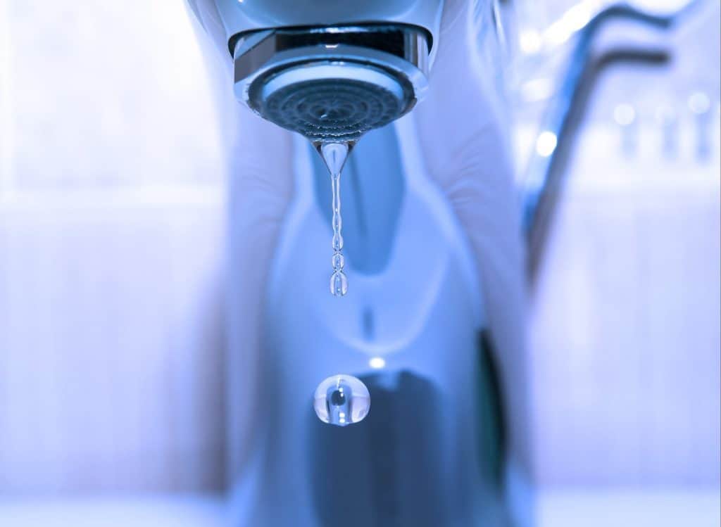 Tropfender Wasserhahn und Wassertropfen – Warmwasser sparen