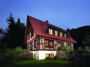 Ein Fachwerkhaus: rotes Dach und farbige Fensterprofile.