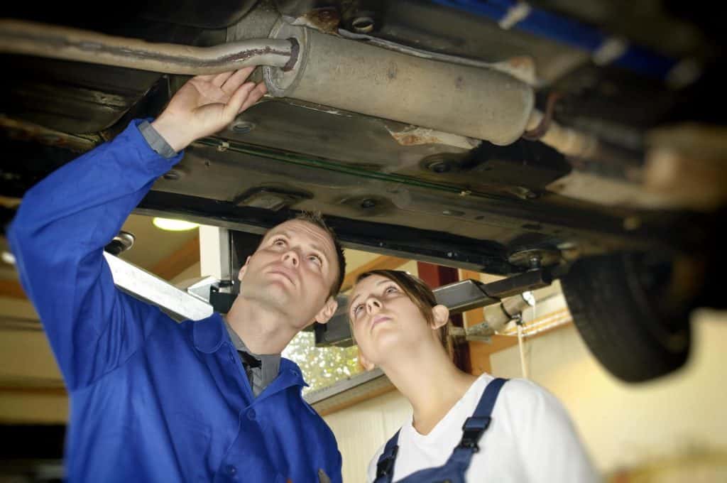 Mädchen im Männerberuf – na und?: KFZ-Meister zeigt der jugendlichen Auszubildenden die Prüfung der Auspuffanlage am Unterboden in der Autowerkstatt.