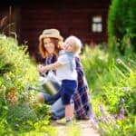 Cottage Gärten - kleines Kind gießt mit seiner Mutter Blumenstauden.