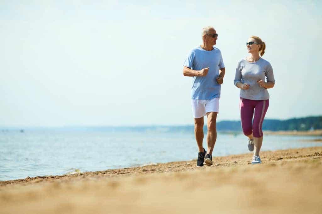 Senior joggt mit Frau am Strand (Joggen für Anfänger)