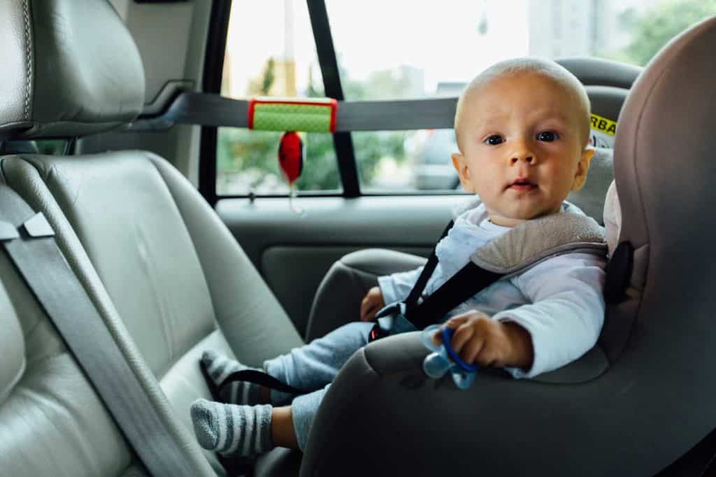 Ein Kleinkindsitzt in einem altergerechten kindersitzt und guckt neugierig in die Kamera. (Autofahren mit Kindern)