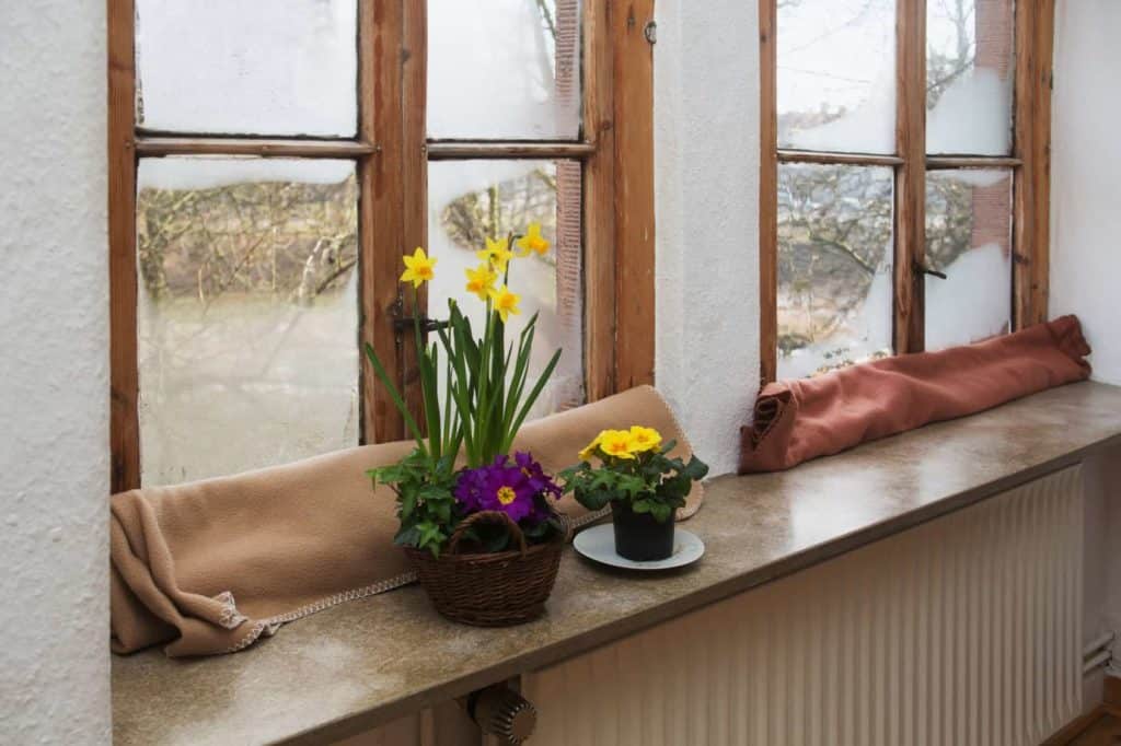 Zeit für den Fenstertausch: altes Fenster mit Wolldecke gegen Zugluft abgedeckt.