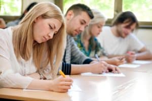 Vier Schüler sitzen nebeneinander und arbeiten (Nach dem Abi).