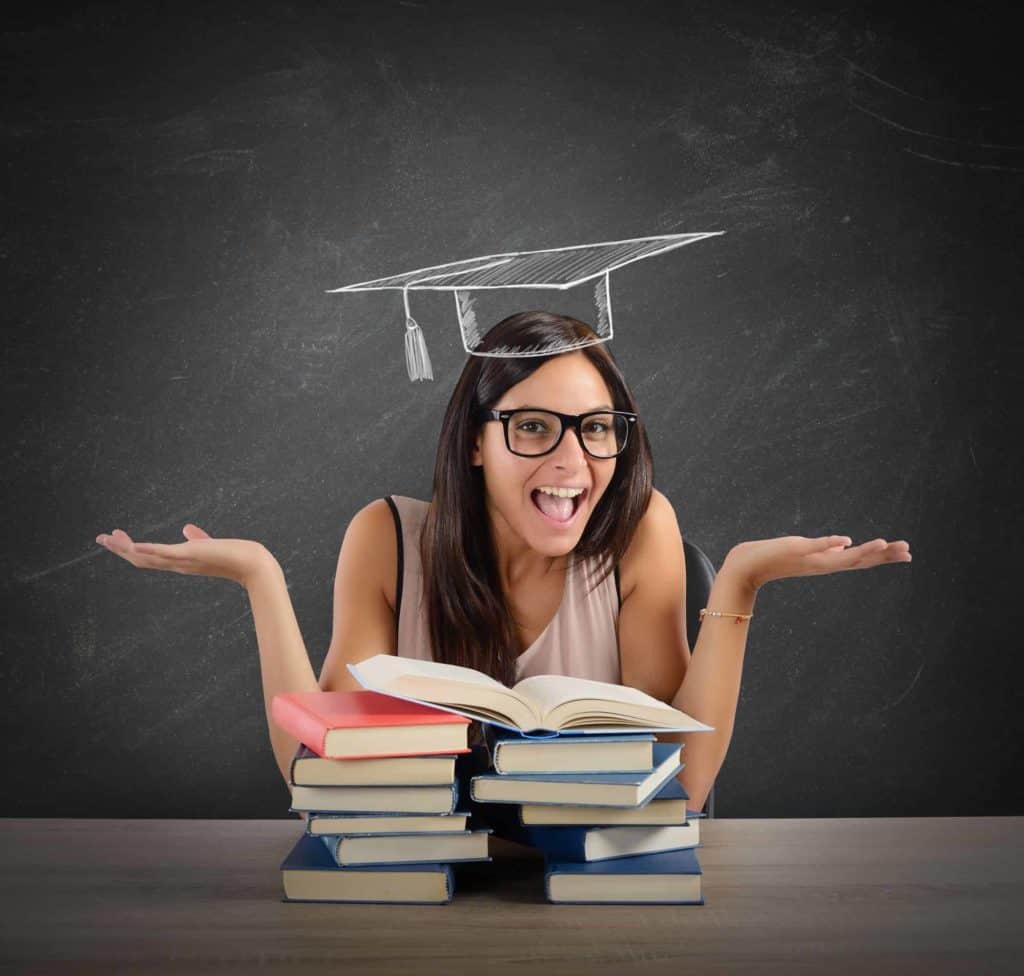 Eine junge Frau sitzt vor vielen Büchern und gestikuliert unentschlossen mit ihren Händen (Nach dem Abi).