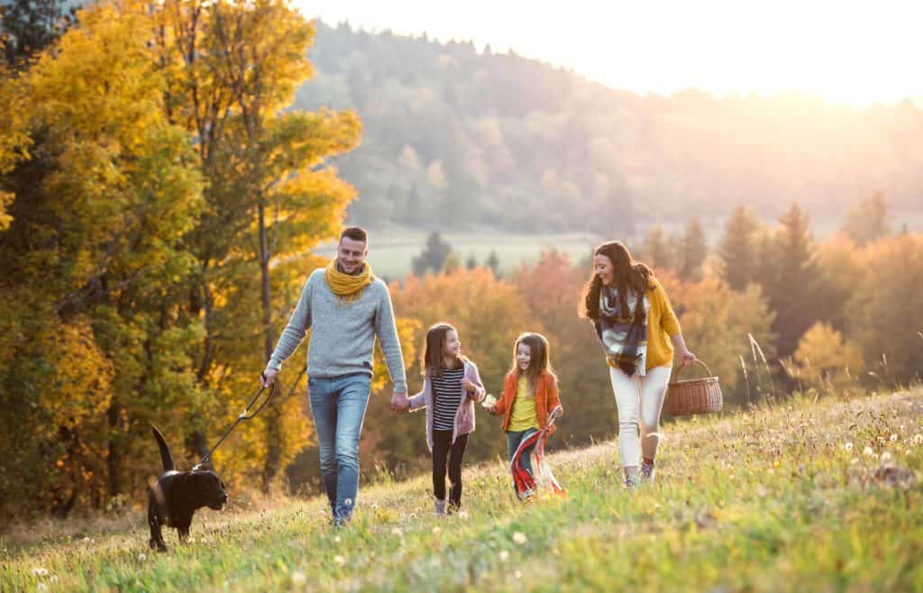 Eine Familie wandert fröhlich durch die Herbstlandschaft.