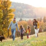 Eine Familie wandert fröhlich durch die Herbstlandschaft.