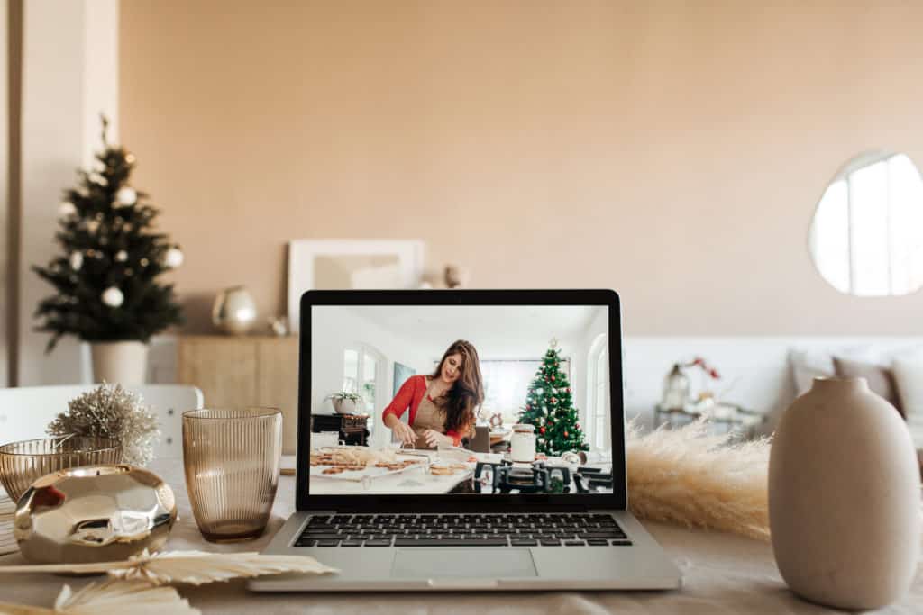 Virtuelle Weihnachtsfeier: über einen Livestream, der auf einem Laptop abgespielt wird, zeigt eine Frau, wie Sie Plätzchen backt.
