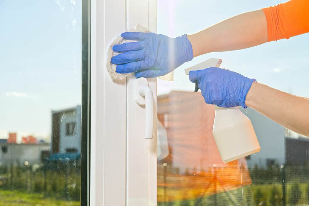 Kunststofffenster reinigen: Kunststofffenster, Hände mit Gummihandschuhen