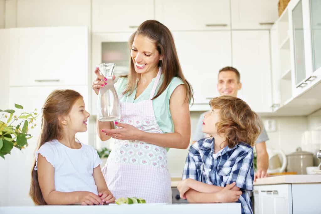 Glückliche Eltern sind mit ihren Kindern in der ordentlichen Küche. 