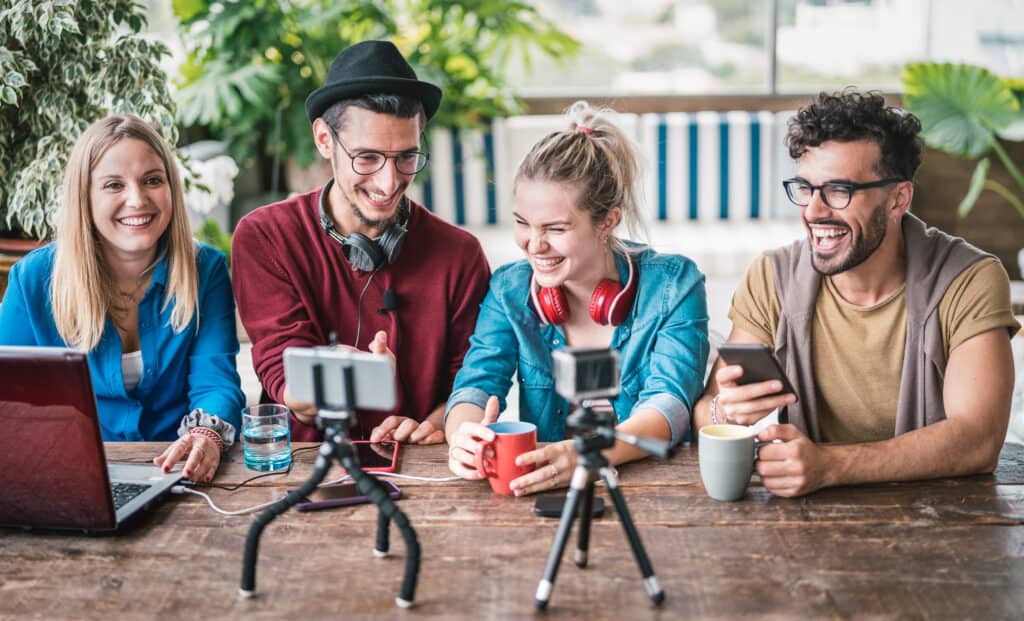 Junge Freundesgruppe der Generation Z am Tisch mit ihren mobilen Geräten