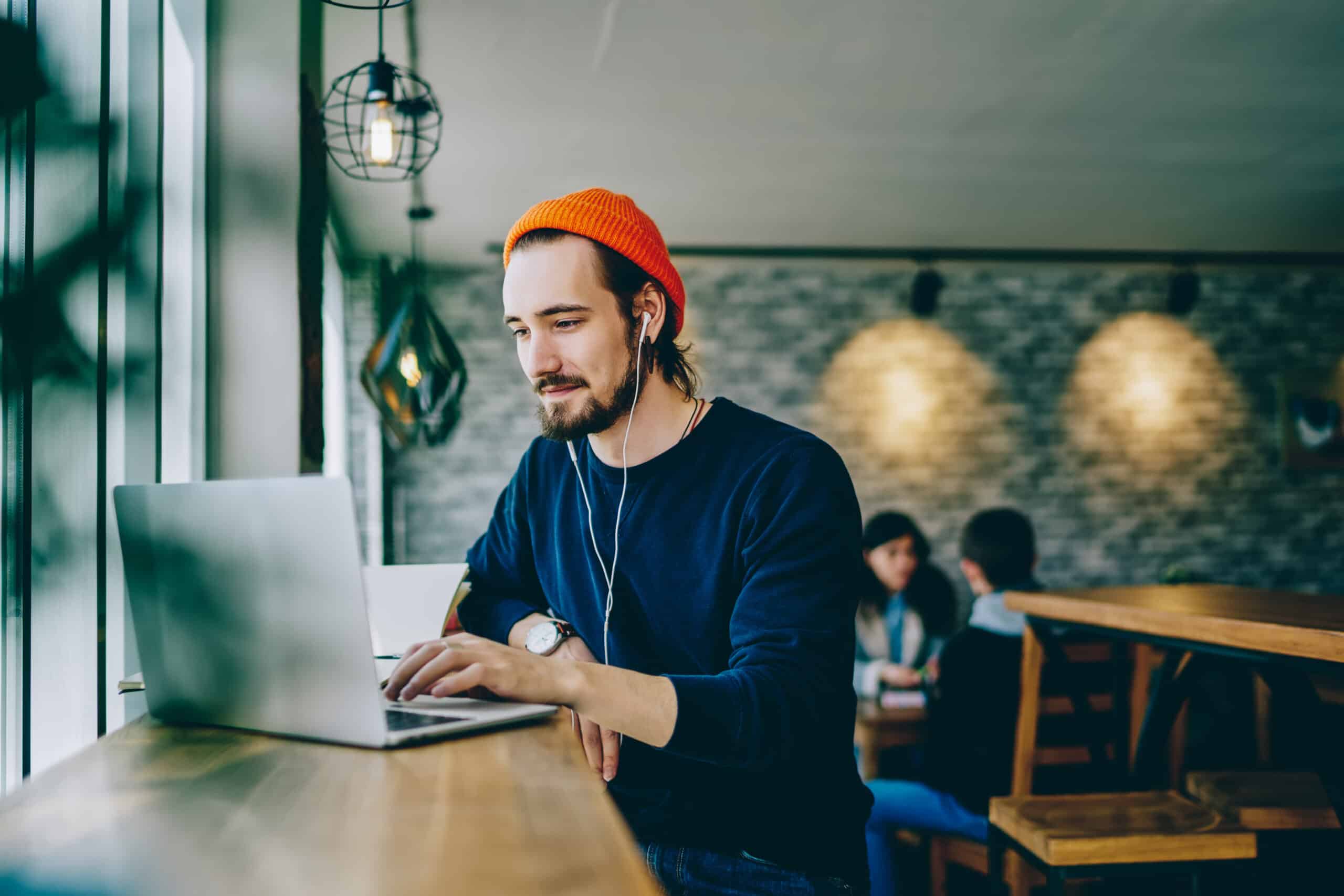 Junger Mann arbeitet im Cafe an seinem Laptop