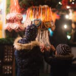 Zwei Kinder schauen sich Lebkuchenherzen auf dem Weihnachtsmarkt in Saarbrücken an.