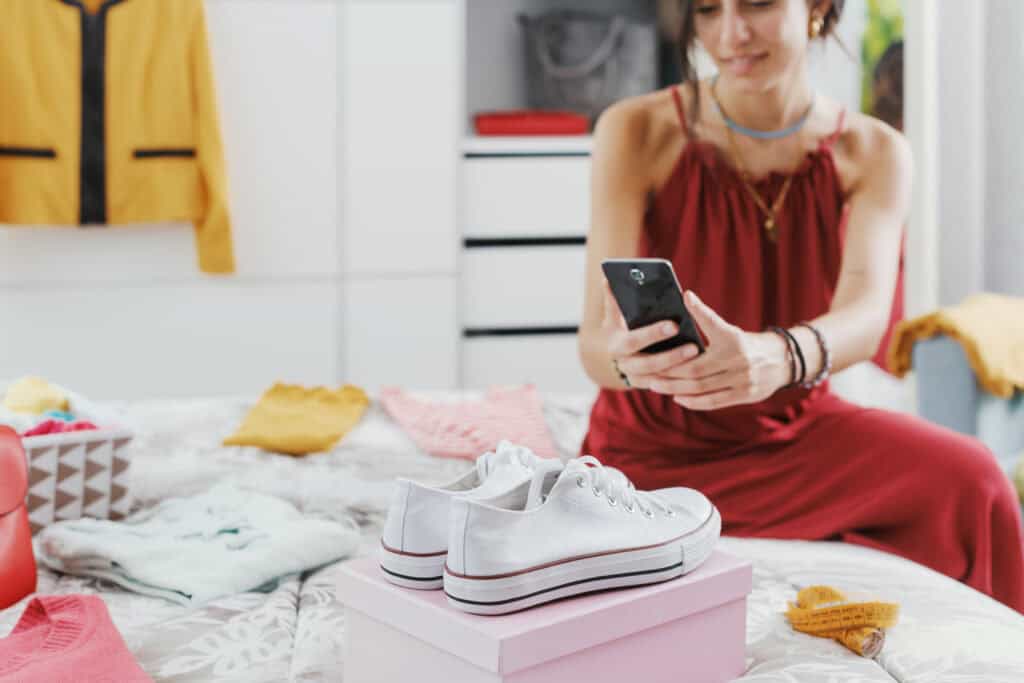 Frau sitzt auf dem Bett und fotografiert Schuhe zum Reselling