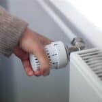 Energieberatung: Eine Hand mit hellem Pullover dreht das Thermostat auf