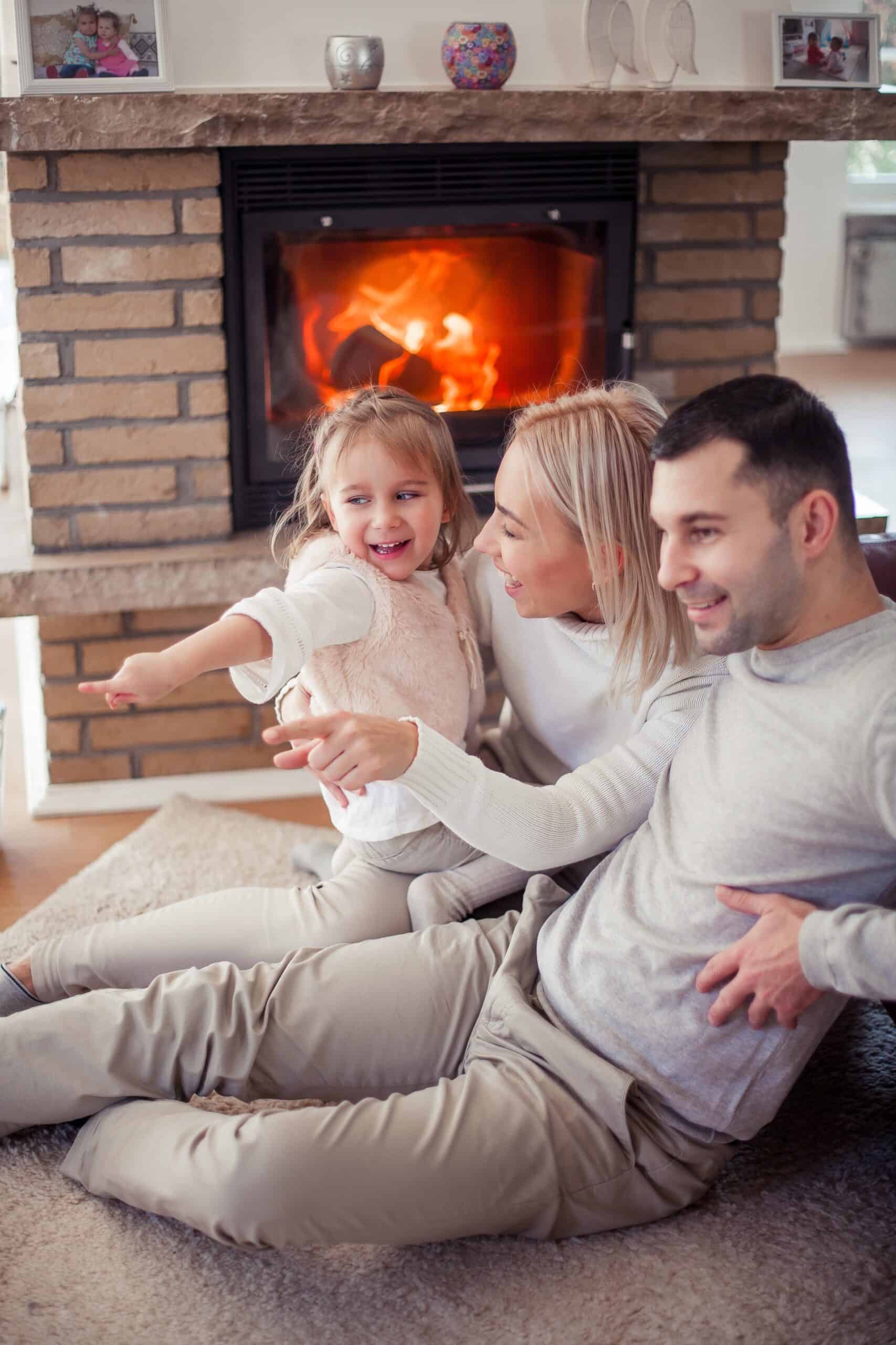 Kamine und Feuerstätten: Das sollten Hausbesitzer wissen Kamine und Feuerstätten: eine Familie glücklich sitzend an Ihrem Ofen