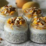 Chiapudding mit Mango, gehackten Mandeln und Joghurt in kleinen Gläsern – angerichtet auf einem weißen Tuch