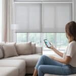smarte Kunststofffenster: Eine Frau mit einem Handy in der Hand steuert ihre Fenster